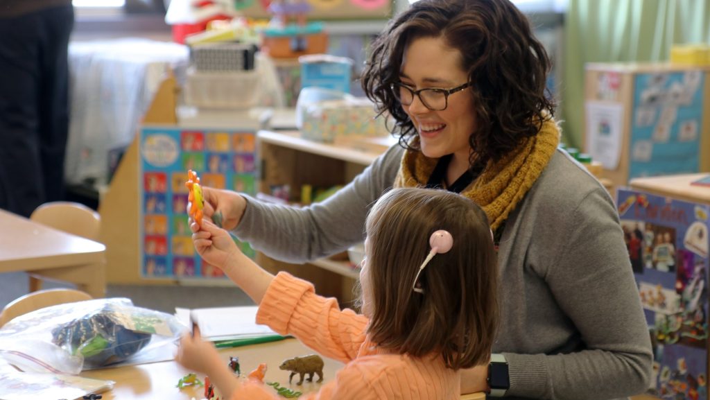 A woman teacher works with a young student