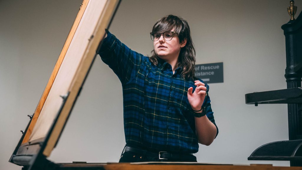 A student uses a nineteenth century printing press